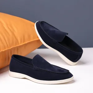Detailed view of men's navy blue suede loafers featuring white soles and decorative stitching