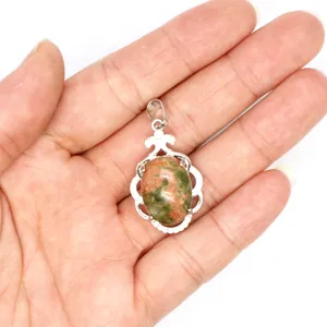 Primer plano de un colgante calado plateado con una piedra ovalada moteada en verde y rosa