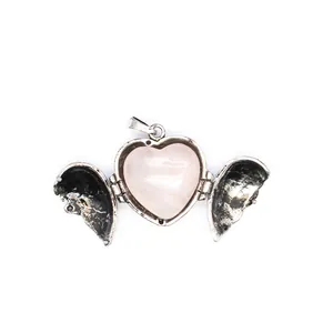 Detailed view of a vintage heart locket with openable angel wings and pink stone