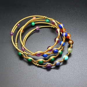 Dettaglio di bracciali rigidi fatti a mano in oro 14K con gemme naturali di vari colori