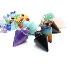 Macro view showing various natural crystal arrowhead pendulums with colorful chakra beads