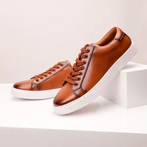 Detailed view of premium brown leather sneakers featuring thick white rubber soles.