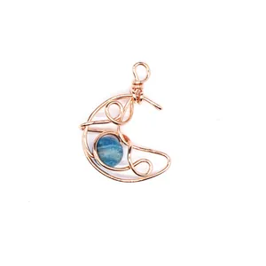 Close-up view of a handmade wire-wrapped crescent moon pendant with blue stone.
