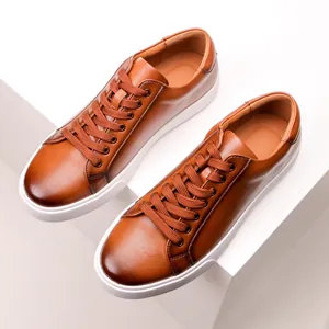 Close-up detail of premium brown genuine leather men's casual sneakers with thick white soles.
