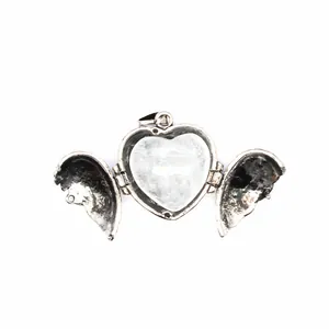 Detail view of a vintage silver heart locket with open angel wings and heart stone.