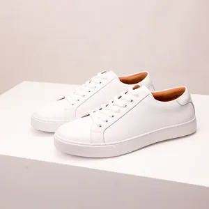 Detailed view of minimalist white leather sneakers for men on a sleek white platform