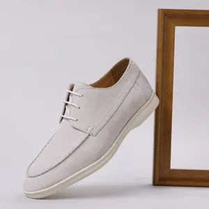 Close-up of light grey suede lace-up men's casual shoes with a white rubber sole