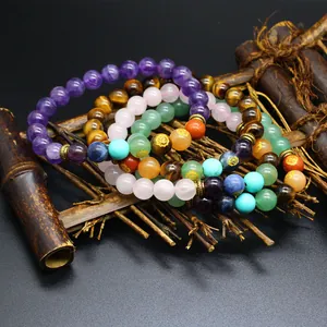 Macro detail of 8mm natural stone chakra bracelets displayed on a rustic bamboo prop