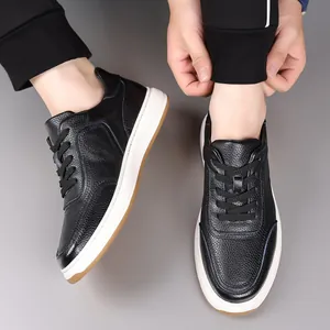 Close-up view of men's black pebbled genuine leather casual sneakers worn with joggers.