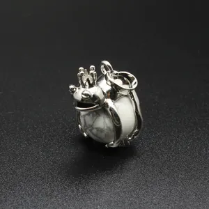 Macro detail of a silver frog prince pendant holding a white natural stone sphere.