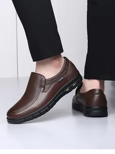 Professional detail view of men's brown leather slip-on loafers worn with black trousers.