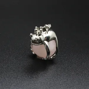 Detailed macro view of silver frog prince pendant hugging a pink natural crystal ball