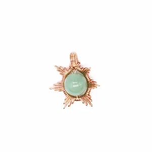 Detailed close-up of a handmade wire-wrapped sun pendant with a green natural stone.