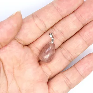 Macro view of a natural strawberry quartz teardrop crystal pendant held in a hand
