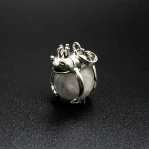 Macro view of a silver-toned frog prince pendant holding a polished natural stone sphere