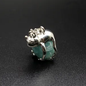 Macro detail of a silver Frog Prince pendant holding a green natural stone crystal ball