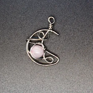 Detail shot of hand-woven silver wire-wrapped crescent moon pendant with rose quartz