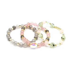 Detail view of three natural stone bracelets with strawberry quartz and gold accents.