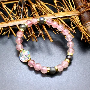 Detail of a handmade strawberry quartz bracelet with a faceted aurora crystal bead.