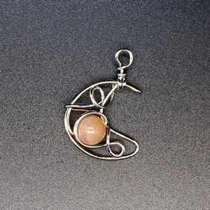 Detailed view of handmade wire-wrapped moon pendant featuring natural sunstone bead