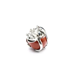 Close-up detail of silver frog prince pendant holding a polished red stone sphere