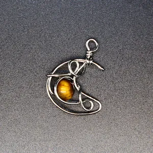 Handmade wire wrapped crescent moon pendant with natural tiger eye gemstone detail.