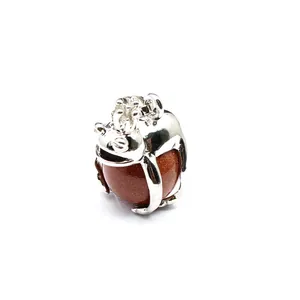 Close-up of a silver-toned frog prince pendant clutching a sparkling goldstone sphere