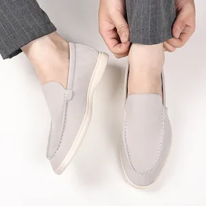 Close-up view of light grey suede-textured men's loafers being adjusted on foot