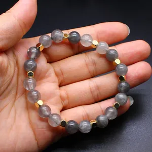 Macro detail view of natural strawberry quartz beads and gold cube spacers on a hand