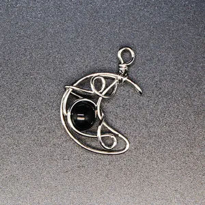 Detailed view of a handmade wire-wrapped moon pendant with a polished black stone