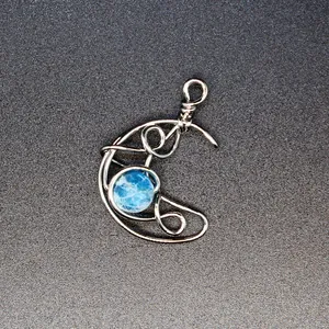 Detailed view of handmade wire-wrapped crescent moon pendant with blue natural stone