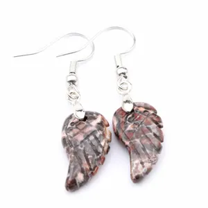 Primer plano de pendientes de piedra natural con forma de ala y ganchos plateados.