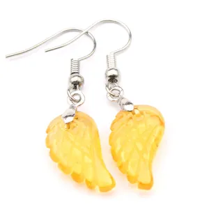Vista detallada de pendientes de ala de cristal amarillo con ganchos plateados