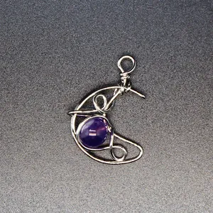 Macro view of hand-woven silver crescent moon pendant with purple natural stone