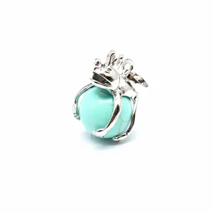 Detailed view of silver frog prince pendant clutching a turquoise stone crystal ball.