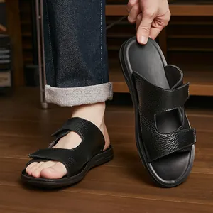 Close-up view of men's black leather slippers featuring adjustable velcro straps on model