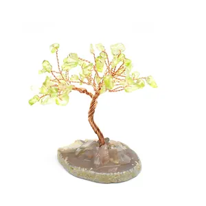 Detail view of peridot crystal tree with copper wire on a natural agate slice base