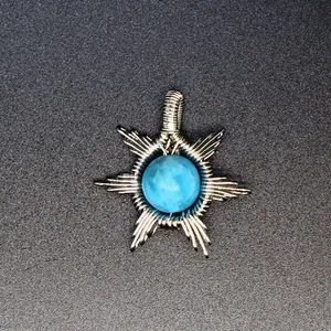 Detailed macro view of handmade wire-wrapped sun pendant featuring faceted blue natural stone