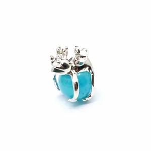 Macro detail view of a silver frog prince pendant holding a blue natural stone bead