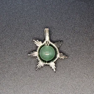 Close-up detail of a handcrafted wire-wrapped sun pendant featuring a green natural stone bead