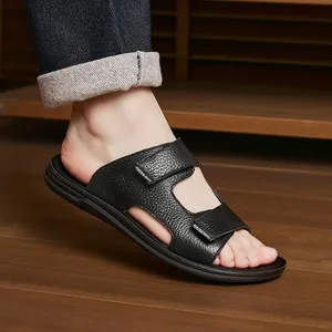 Close-up of men's black leather-textured slides with double straps on wooden floor