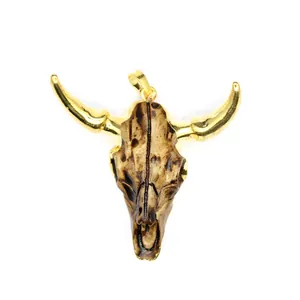 Vista detallada de un colgante de calavera de toro de resina con cuernos dorados.