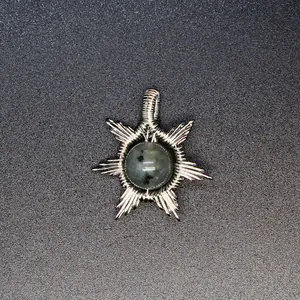 Detailed view of hand-woven wire wrapped sun pendant with natural grey stone inlay.