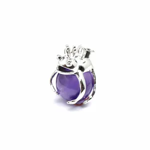 Macro detailed view of silver-tone frog prince pendant holding a purple crystal stone bead