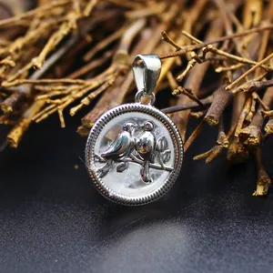 Gros plan d'un pendentif oiseau rond argenté avec incrustation de cristal naturel