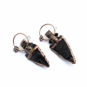 Detailed macro view of handmade obsidian stone arrowhead pendants with vintage copper plating