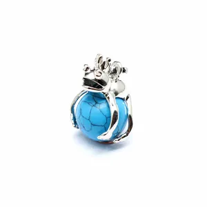 Detailed macro shot of silver frog prince pendant holding a blue turquoise sphere
