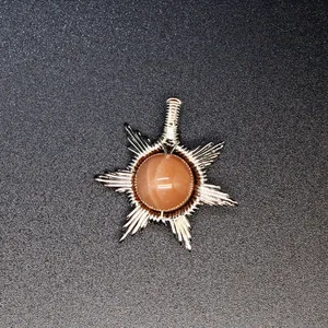 Macro view of hand-woven wire-wrapped sunstone pendant with intricate starburst design