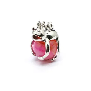 Close-up detail of a polished silver frog prince pendant holding a vibrant pink crystal ball.