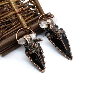 Macro detail of Gothic crow skull obsidian arrowhead pendant with raw crystal.